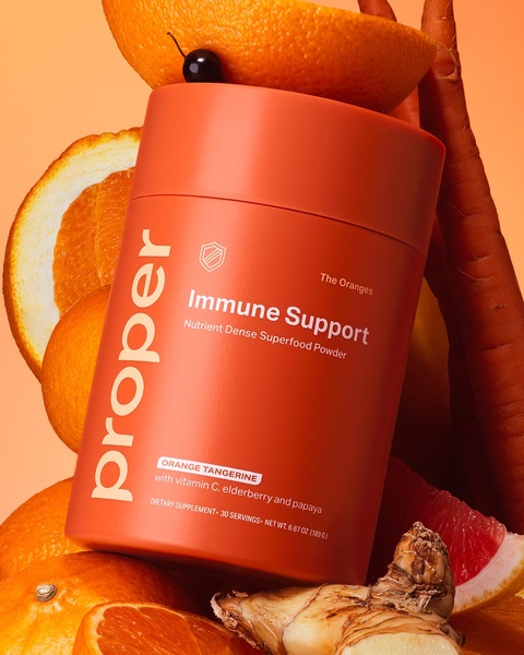 A high-quality product shot featuring an Immune Support powder container surrounded by raw, fresh ingredients like oranges and ginger.